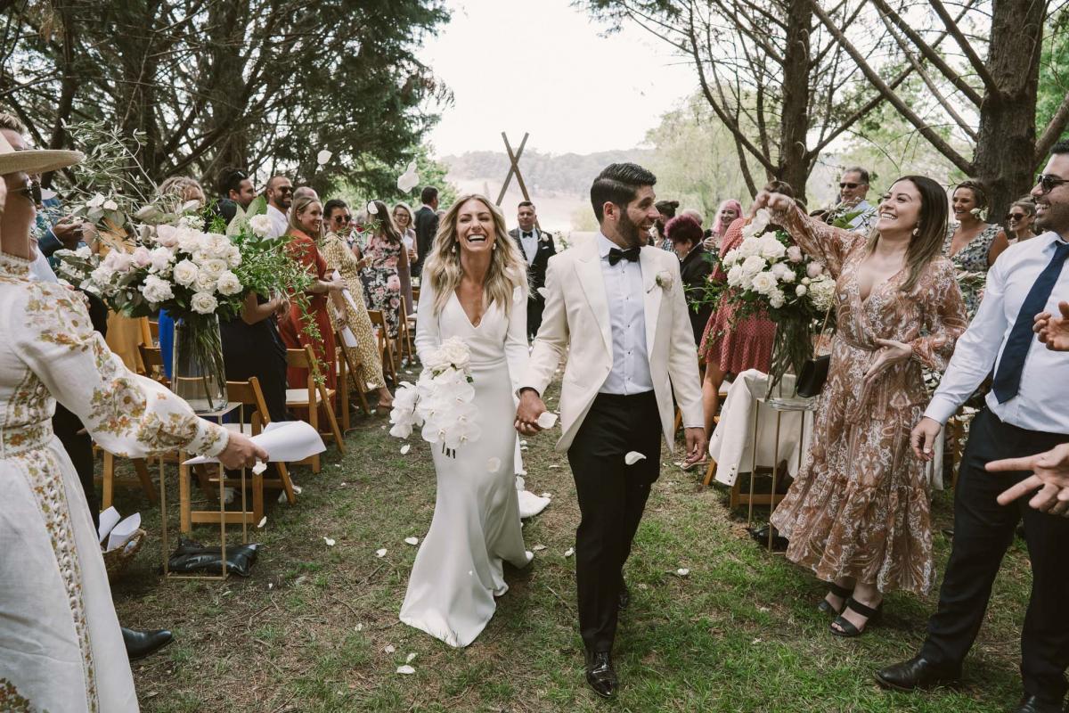 Real couple Annabelle and Marc just married at family farm ceremony, bride wearing the Aubrey gown by Karen Willis Holmes; a simple wedding dress with long sleeves and a shoulder pleat.