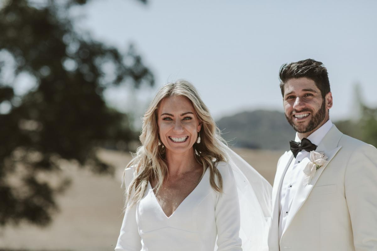 Real bride Annabelle at country farm wedding wearing the long sleeved Aubrey gown and earrings from Pierre Winter Fine Jewels.