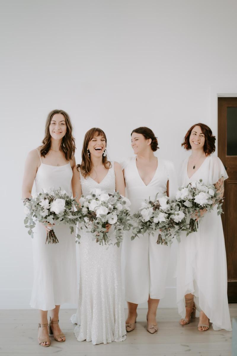 Bride Ania in Karen Willis Holmes Lola Wedding dress posing with native bridal bouquet with bridesmaids in white