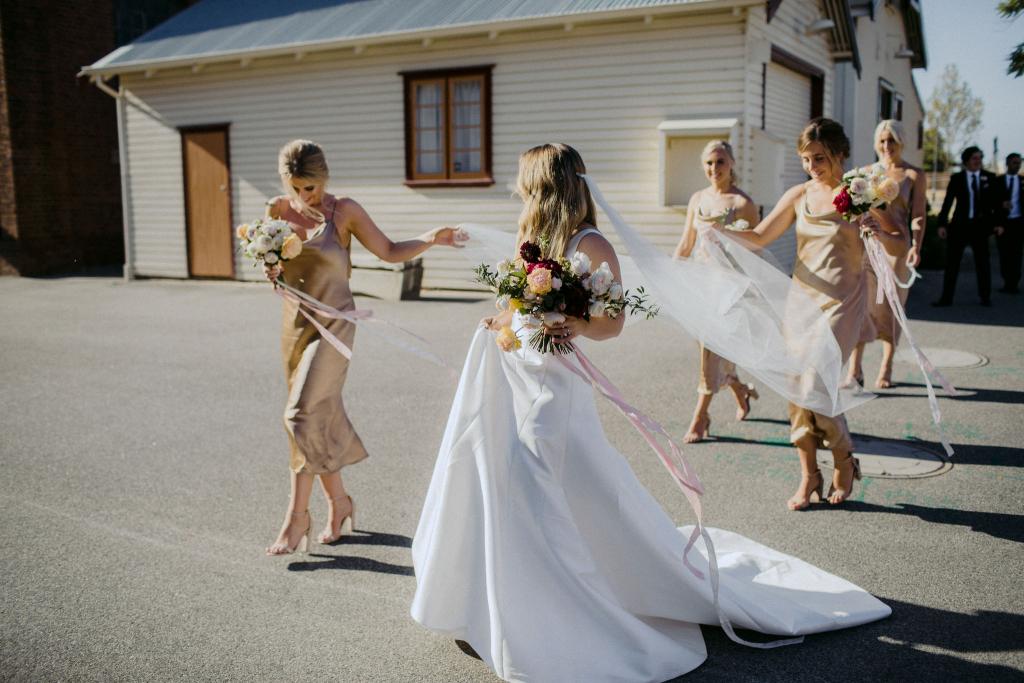 KWH bride Hannah with her bridesmaids, holding a vibrant bouquet & wearing the Taryn Nina gown; a Bespoke wedding dress with sexy edge.