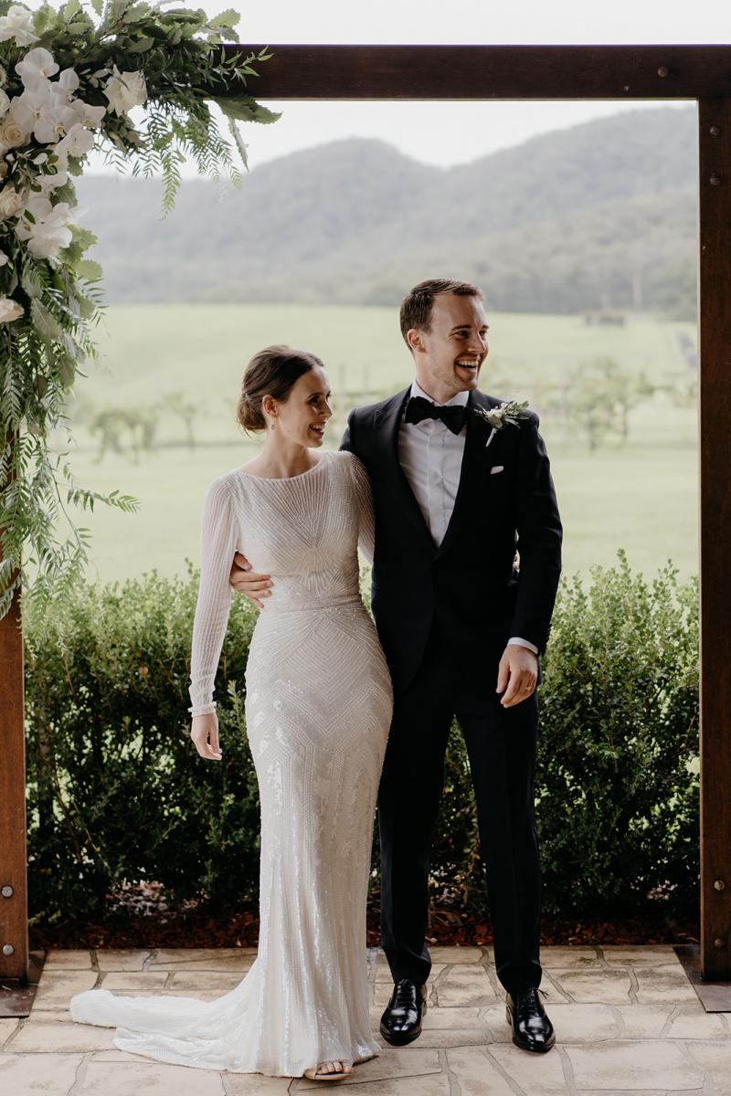 KWH bride Anna and husband Julian standing under their wedding arbour. Anna wears the Cassie wedding dress.