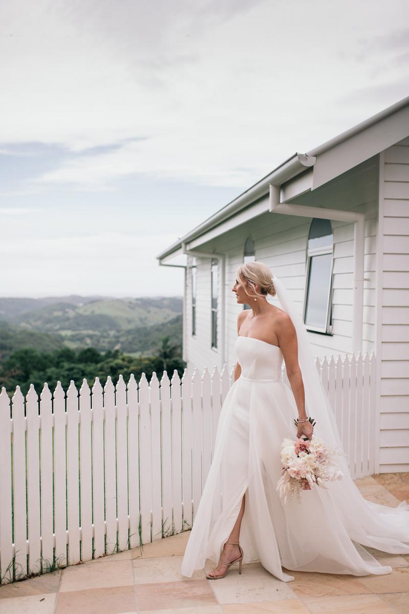 KWH bride Samantha holding her timeless bouquet, wearing the Esther wedding dress which features a front split, fitted base and long train.