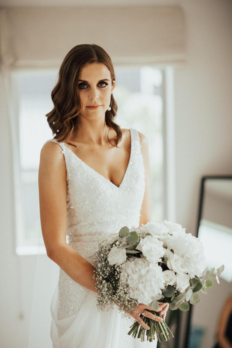Real KWH bride Tash wears the Lola gown with Genevieve trains whilst holding a white and green foliage bouquet.