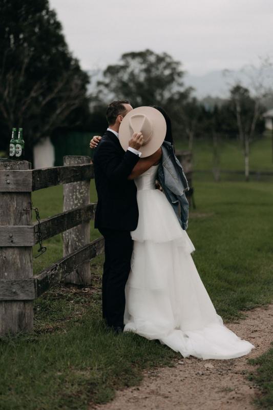 KWH couple sharing a kiss at their country wedding, real bride wearing the Taryn bodice and Marina skirt, a Bespoke wedding dress by Karen Willis Holmes.