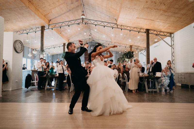 KWH couple Sarah & Phil dancing at real wedding reception, bride wearing the Taryn Marina Bespoke wedding dress, featuring a v-neck bodice and dramatic skirt.