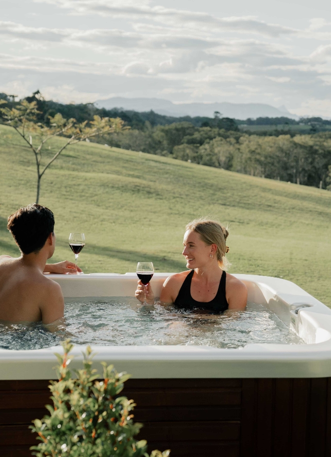 Couple sitting in spa with wine best honeymoon destinations Australia Cape Byron Retreat