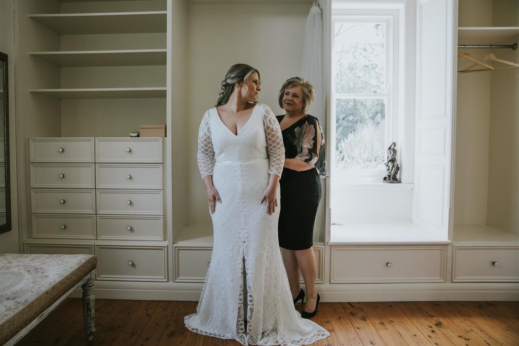 Curvy bride Lucy getting ready on her wedding day, wearing the Bobby gown with custom sleeves; a modern lace wedding dress by Karen Willis Holmes.