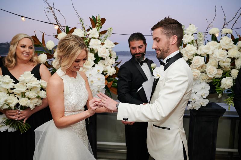 Real bride Claire wears the Cindy gown, a beaded halterneck wedding dress by Karen Willis Holmes to her Sydney wedding, holding an all white bouquet.