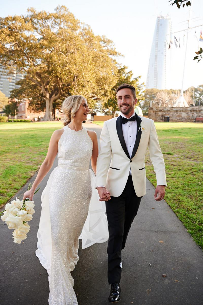 Real bride Claire wears the Cindy gown, a beaded halterneck wedding dress by Karen Willis Holmes to her Sydney wedding, holding an all white bouquet.