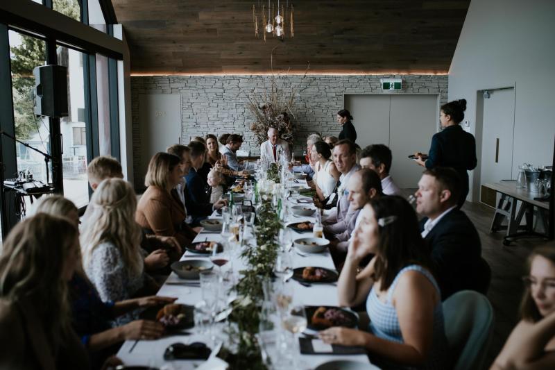 KWH bride Lauren and husband Will under an umbrella. Lauren holds a timeless bouquet and wears the Nikki wedding dress.