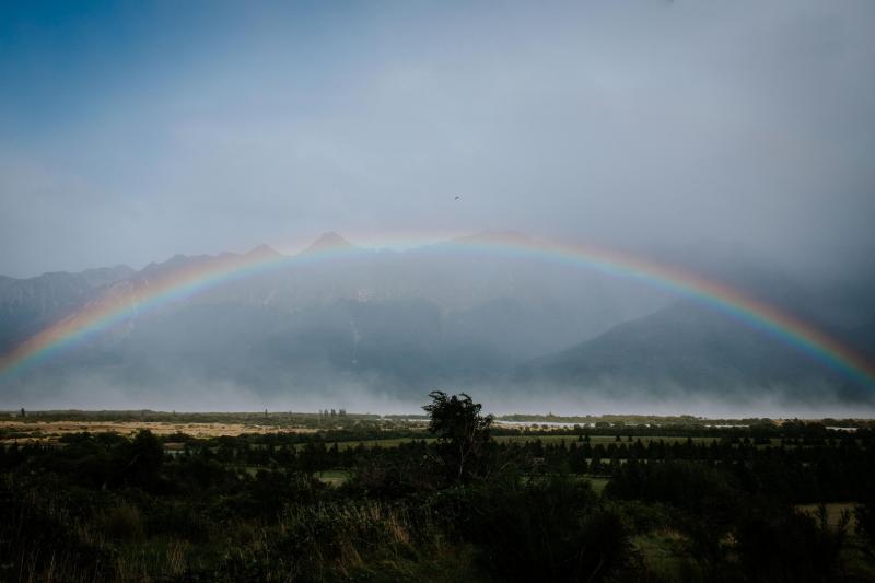 A rainbow stretches across the rugid New Zealand landscape on KWH Real Bride Lauren's wedding day.