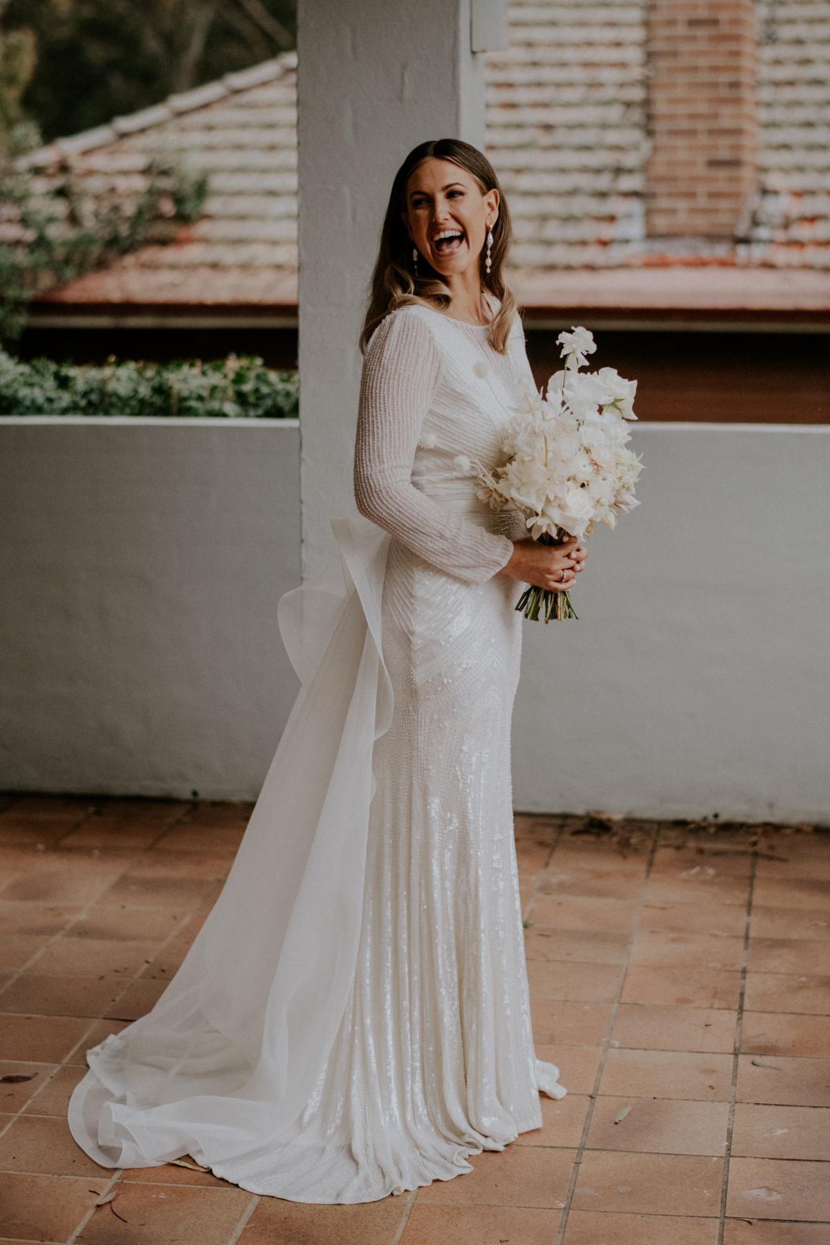 Real bride Penelope wears the Cassie gown; a long sleeve art deco beaded wedding dress from the Luxe collection by Karen Willis Holmes, along with the Oval detachable trains.