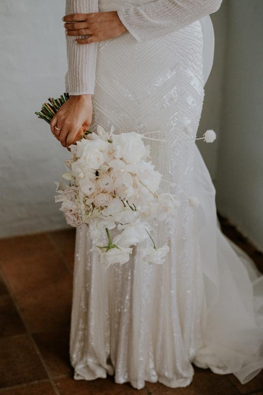 Real bride Penelope poses with white modern bridal bouquet, wearing the Cassie gown; a long sleeve beaded wedding dress by Karen Willis holmes.