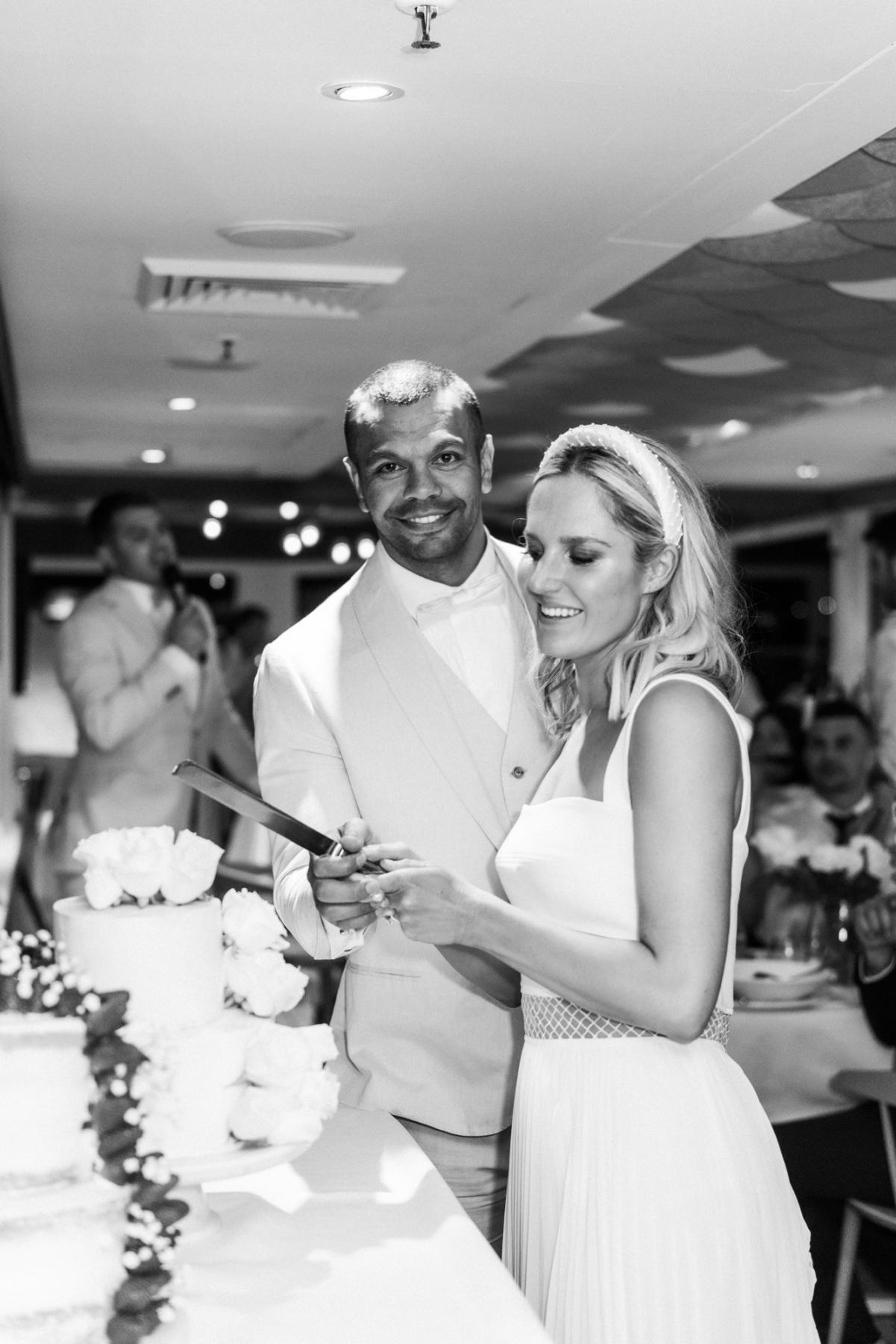 Real bride Maddi cutting cake at real wedding reception wearing the Daisy gown, a non traditional modern wedding dress by Karen Willis Holmes.