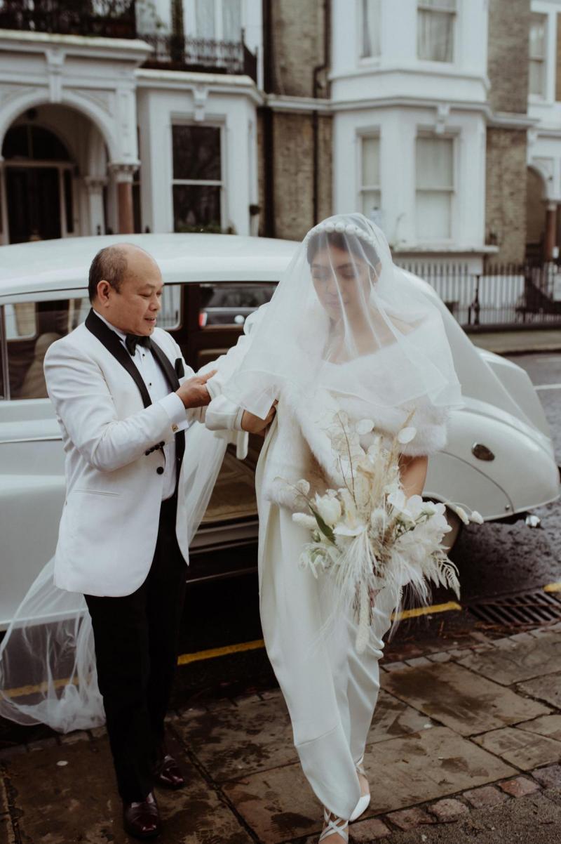 New couple get into vintage wedding car in Karen Willis Holmes wedding dress and cathedral veil in London