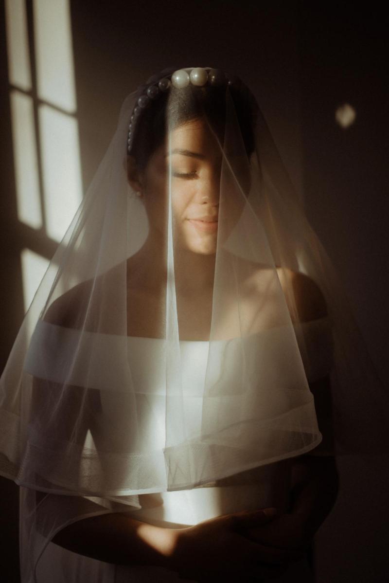 KWH bride Bonita getting ready. Wearing the off-the-shoulder Lauren wedding dress; with an open back and button details..