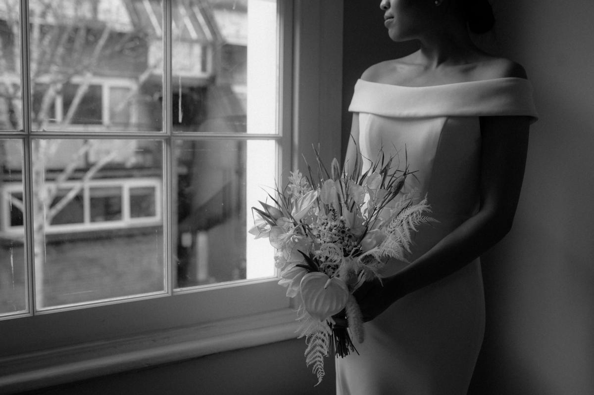 KWH bride Bonita getting ready. Wearing the off-the-shoulder Lauren wedding dress; with an open back and button details..