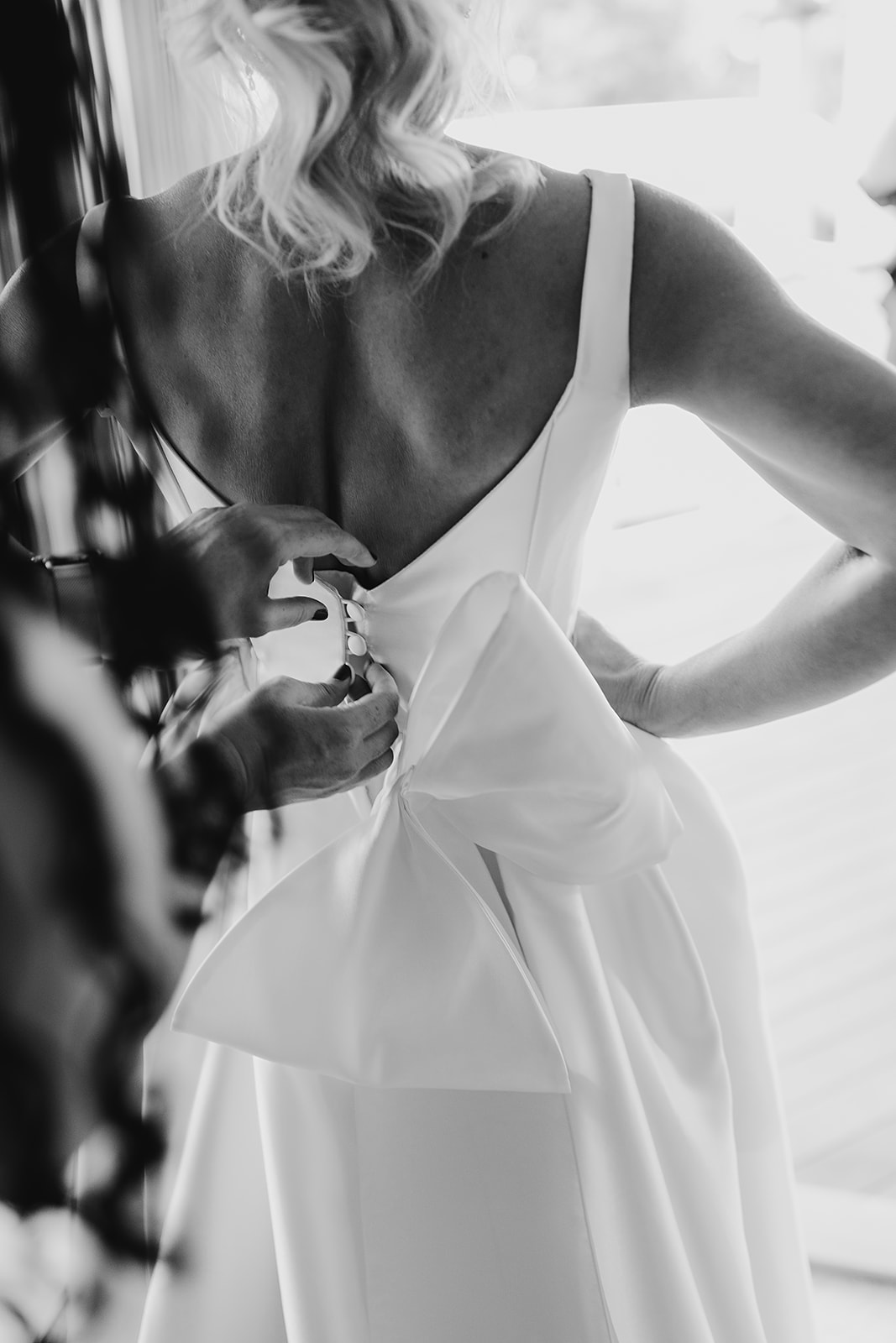 Real bride Caroline getting ready for her wedding, wearing the Taryn Camille gown with custom bow; a modern a-line wedding dress by Karen Willis Holmes.