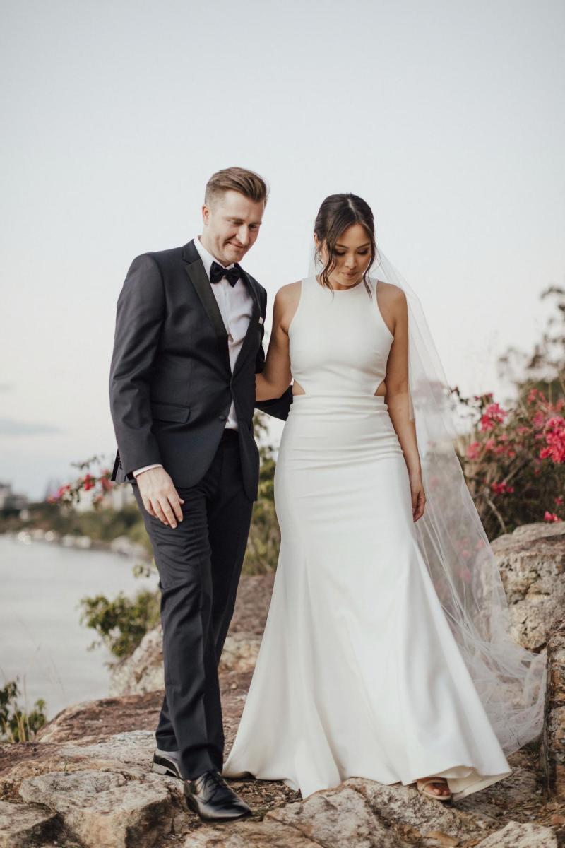 Real bride Melissa with husband at small wedding ceremony on cliff edge, wearing the Bridget gown by Karen Willis Holmes.