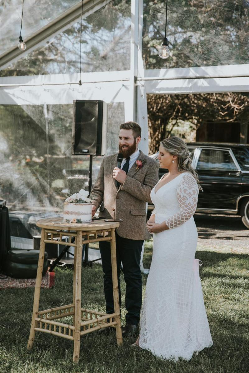 Real bride Lucy wears the Bobby gown with sleeves by Karen Willis Holmes to small backyard wedding ceremony., posing with husband for speeches.