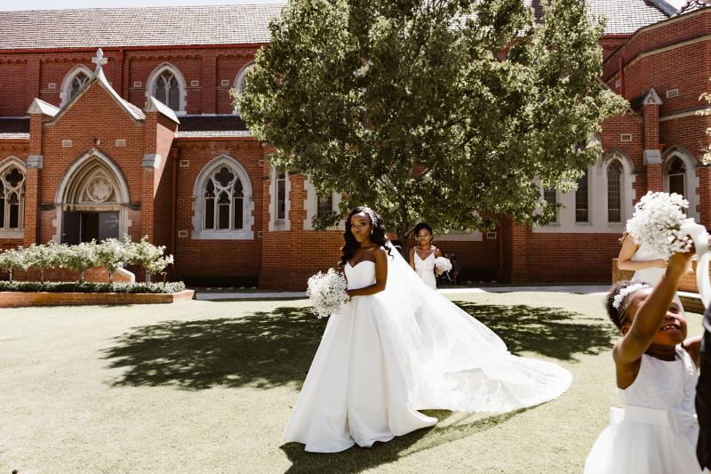 Real bride Ancille stands next to new husband dar at the alter. She wears the timeless Kitty Melanie gown from KWH which features a sweetheart neckline and full aline skirt.