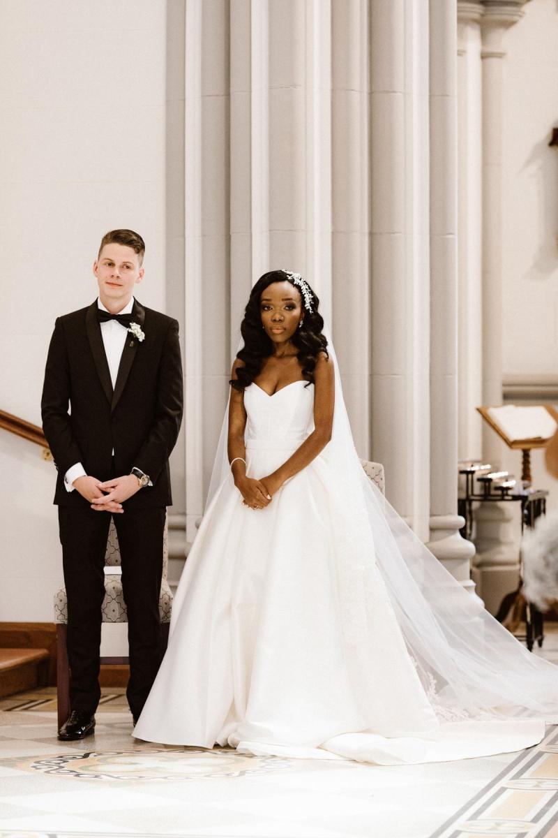 Real bride Ancille stands next to new husband dar at the alter. She wears the timeless Kitty Melanie gown from KWH which features a sweetheart neckline and full aline skirt.