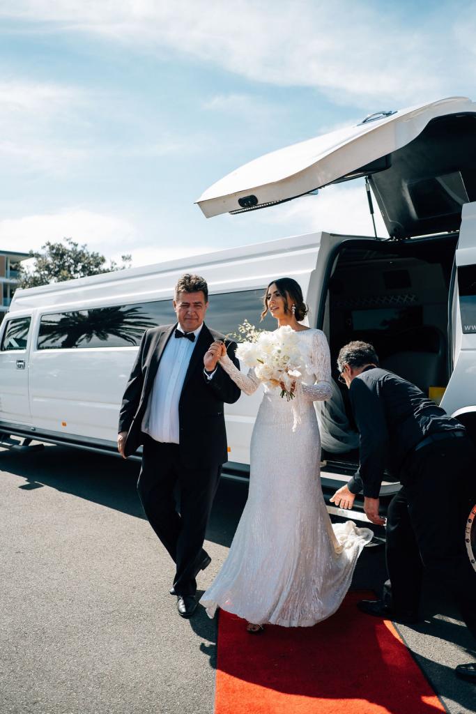 Real bride Katrina arriving to church wedding in white hummer, wearing the Margareta gown, a long sleeve wedding dress by Karen Willis Holmes.