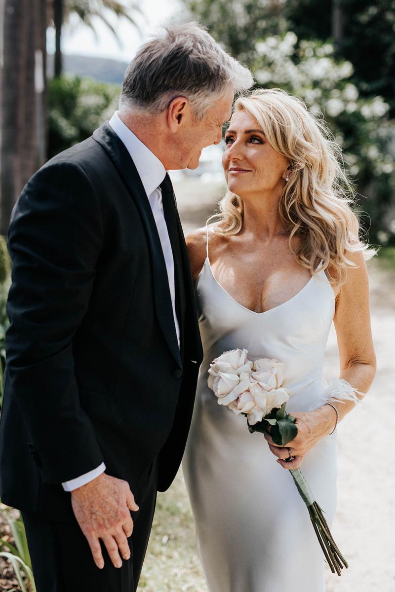 Real bride Wendy poses with husband, wearing the Sage gown, a simple silk satin slip wedding dress by Karen Willis Holmes.