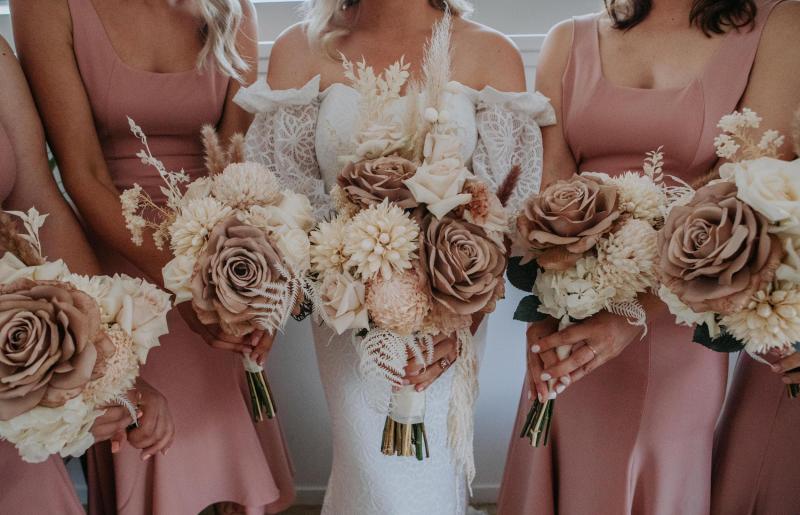 Real bride Kacie-Lee poses with bridesmaids wearing blush dresses, bride wearing the Vivienne gown by Karen Willis Holmes holding natural toned bridal blooms.