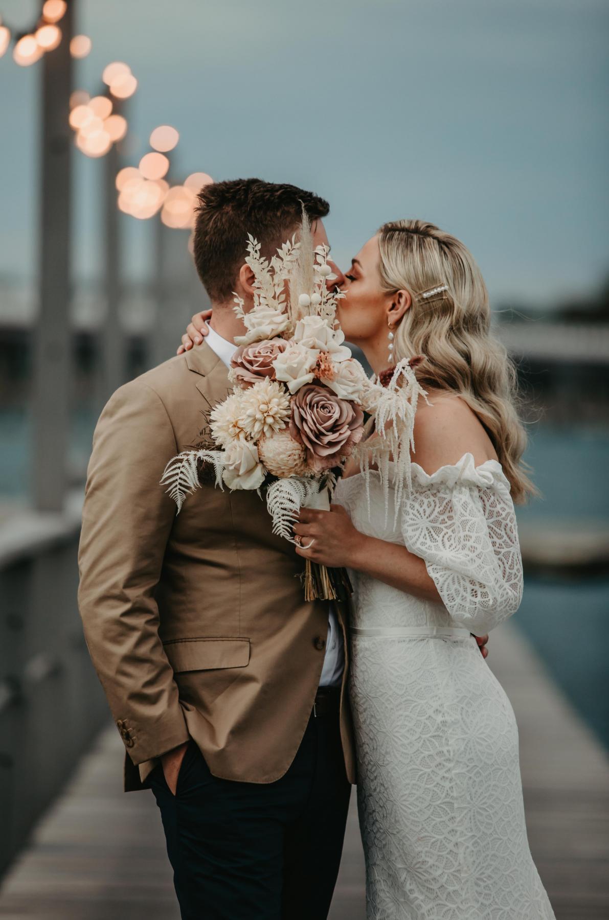 Real bride Kacie-Lee wears the Vivienne gown; a puff sleeve lace wedding dress by Karen Willis Holmes to beach wedding with natural toned bridal blooms.