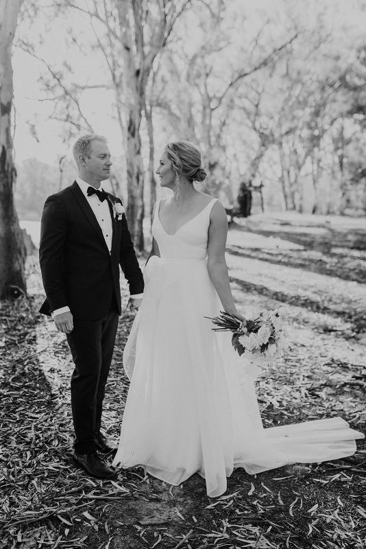 Real bride Samantha poses with her husband for wedding portraits, wearing the Aisha gown by Karen Willis Holmes; a V-neck A-line wedding dress made of honeycomb mesh fabric.