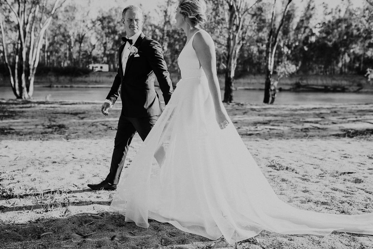 Real bride Samantha poses with her husband for wedding portraits, wearing the Aisha gown by Karen Willis Holmes; a V-neck A-line wedding dress made of honeycomb mesh fabric.