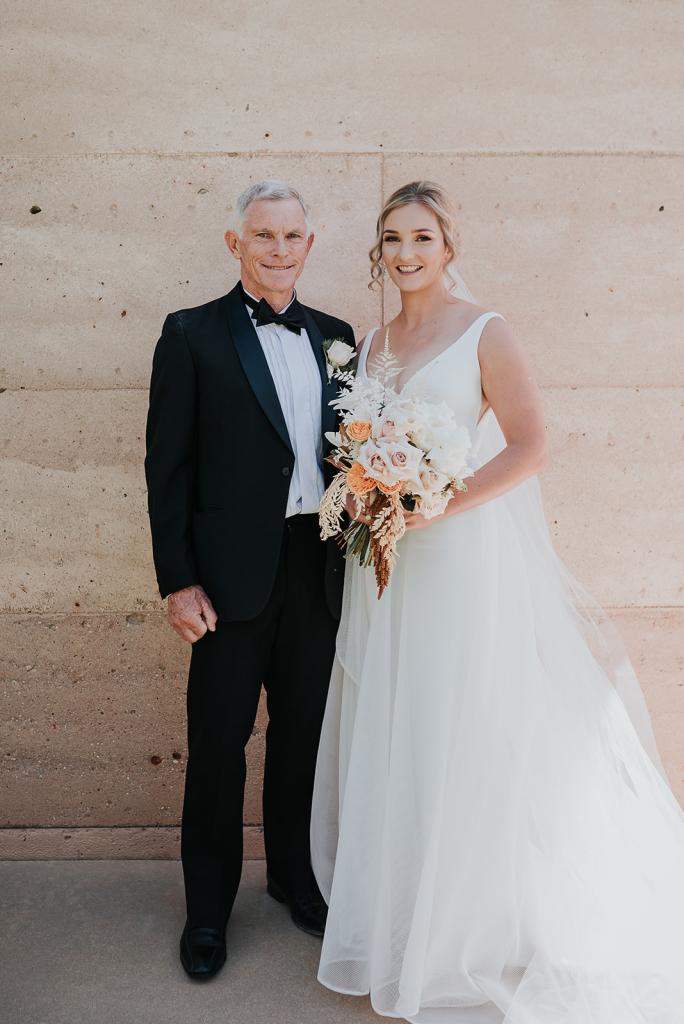 Real bride Samantha poses with Father wearing the Aisha gown by Karen Willis Holmes with bright coloured bouquet.