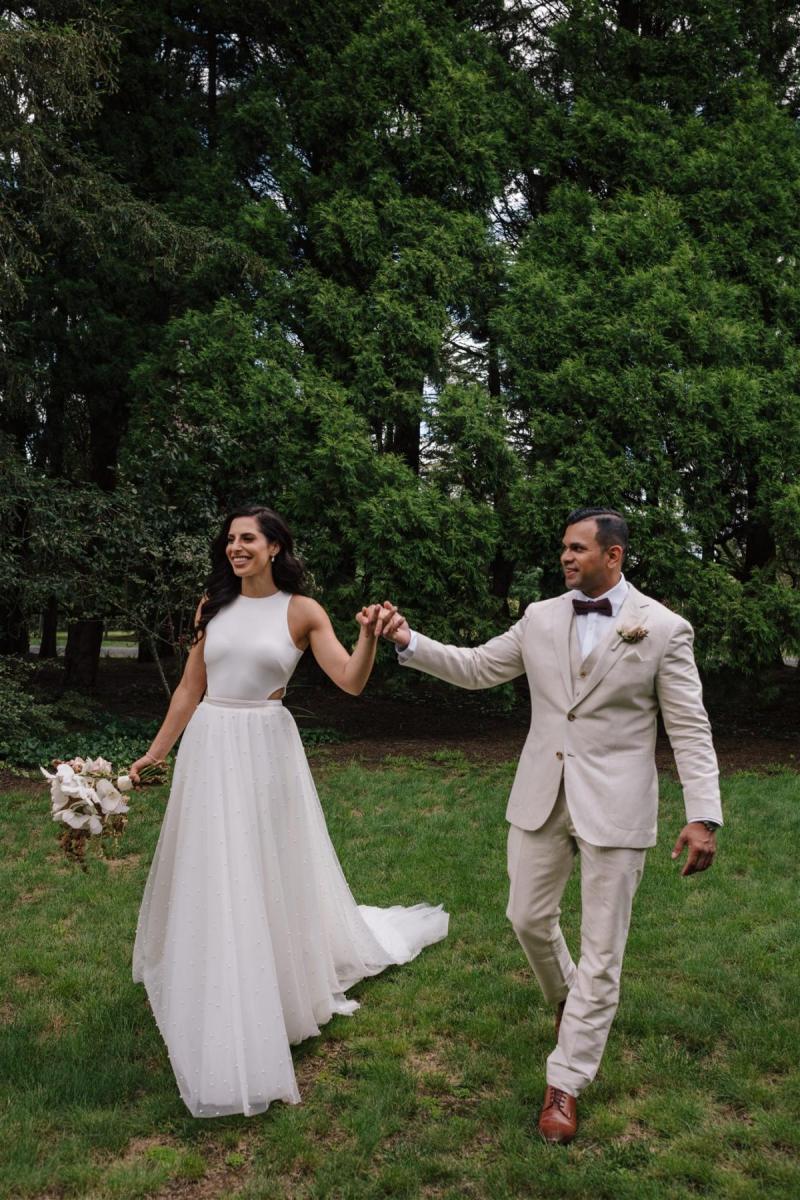 Real bride Marianne with her new husband in the garden, wearing th Bridget gown; a minimal halterneck wedding dress with the Lea pearl skirt by Karen Willis Holmes.