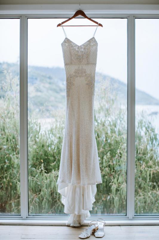 Real bride Ruby's sequin Darcy dress by Karen Willis Holmes hung up on display in front of a scenic window.