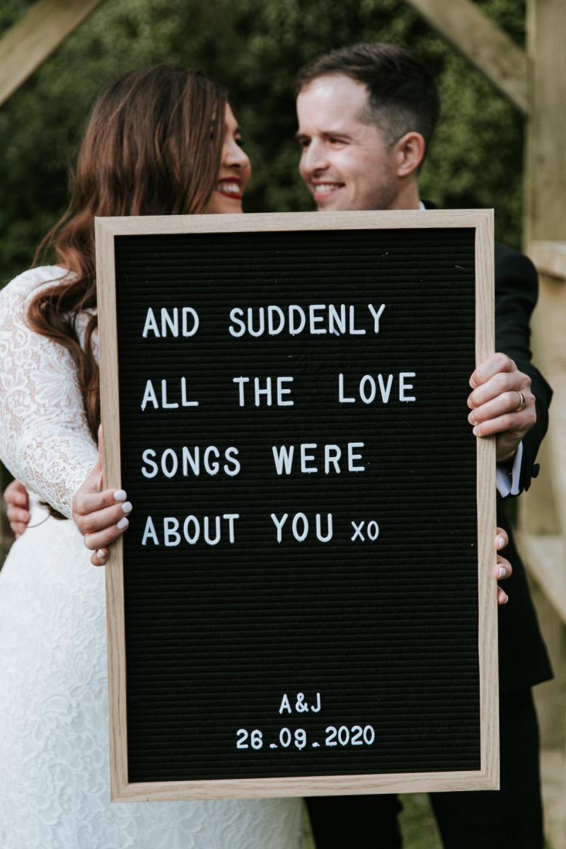 Real bride Jarna and husband Aden holding sign saying, 