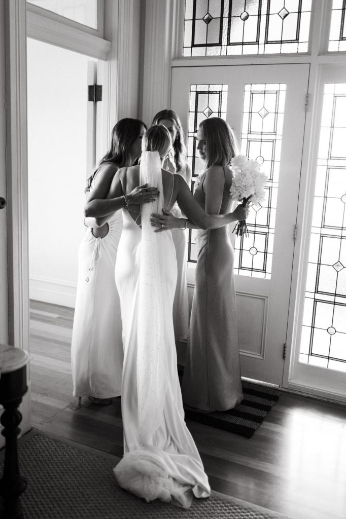 Riley, KWH real bride, hugging her bridesmaids after putting on her modern Sage dress from Karen Willis Holmes.