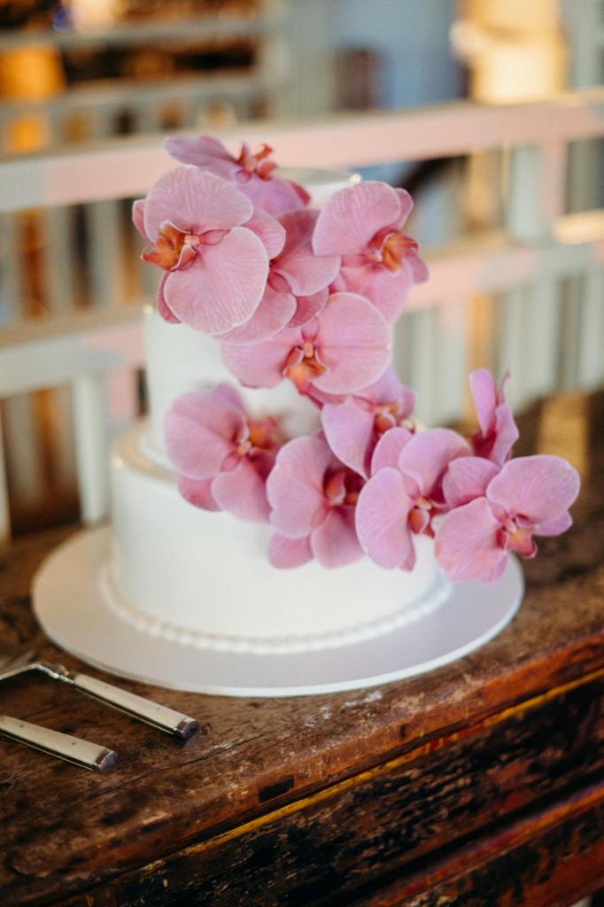 Real bride Riley's white wedding cake decorated with pink orchids by Boutierre Girls.