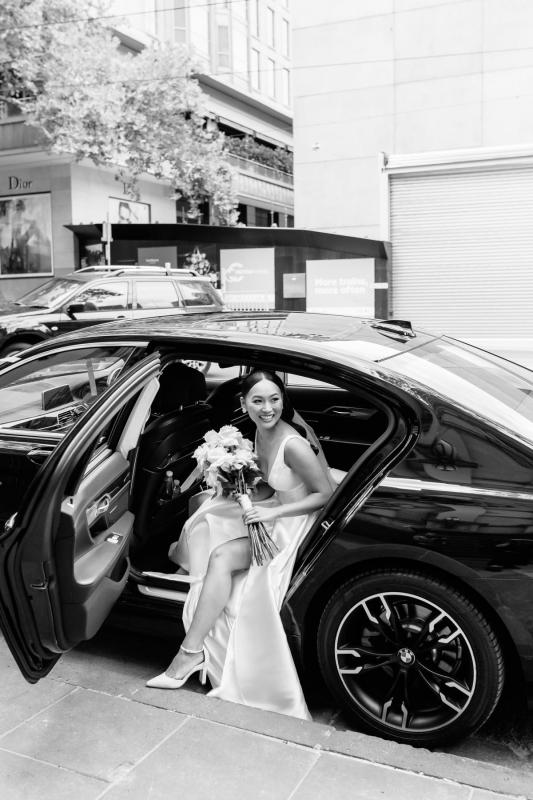 KWH real bride Anna stepping out of a black car in her Taryn Camille gown with U-shaped neckline