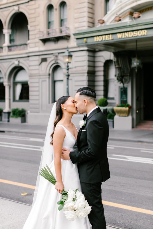 Real bride Anna and Matt kissing in the streets of Melbourne. She dons the ivory Taryn Camille KWH gown with pockets!