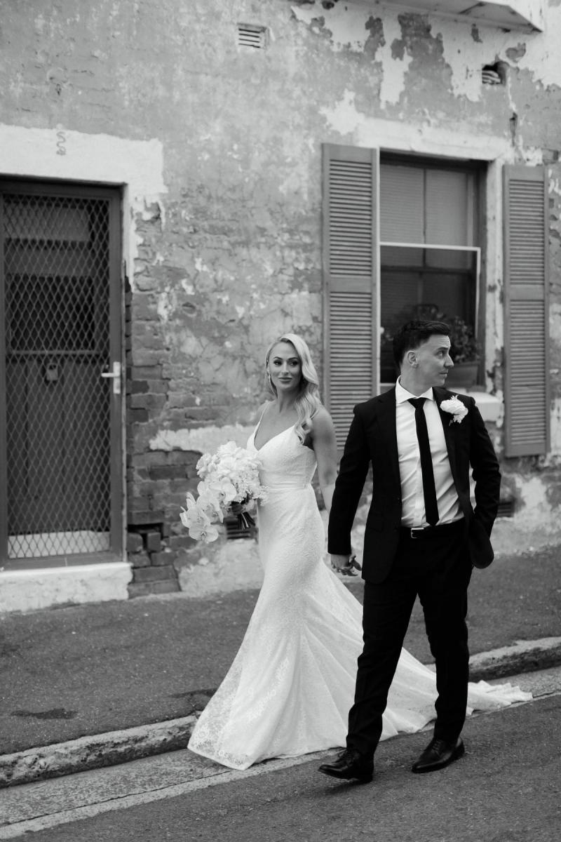 Real bride Nicole and Chris walking down the street in Manly. She wears the simple Justine gown by KWH.