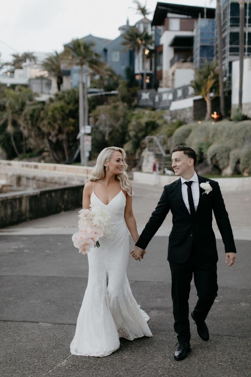 Real bride Nicole and Chris walking down the street in Manly. She wears the simple Justine gown by KWH.