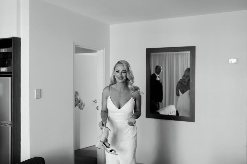 KWH real bride Nicole getting ready in her hotel room. She wears the timeless Justine gown with v-neck and plunging back.