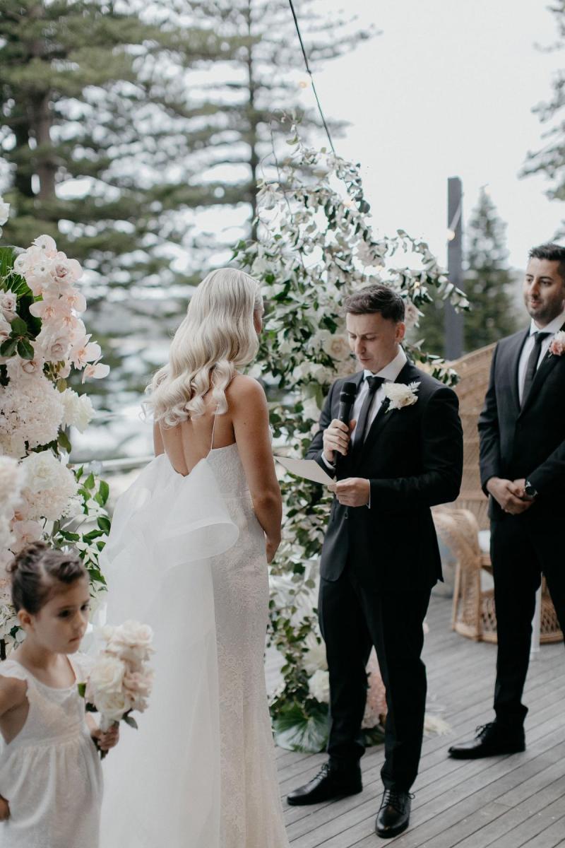 Real bride Nicole stands at the alter with her fiance as they exchange vows. She wears the simple Justine gown with detachable Odette train.