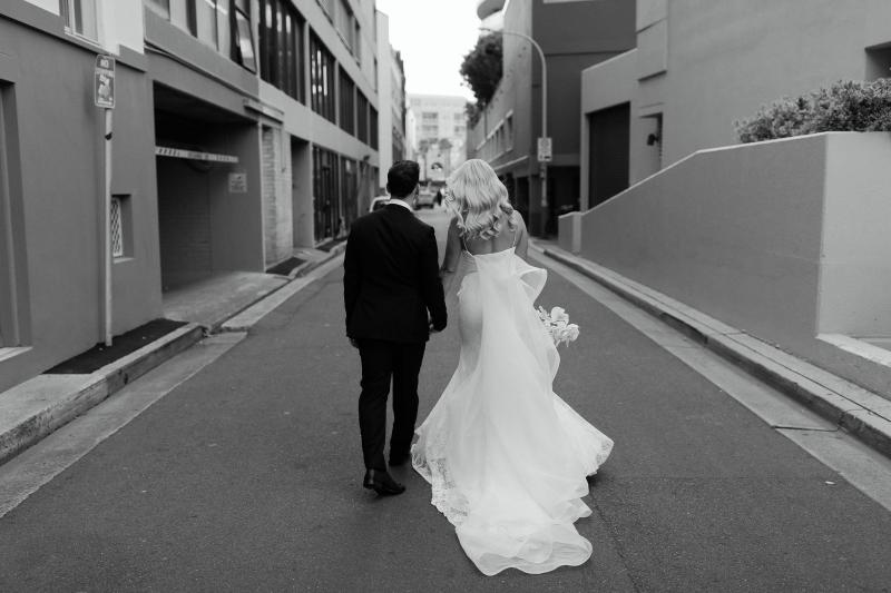 Real bride Nicole and Chris walking down the street in Manly. She wears the simple Justine gown by KWH.