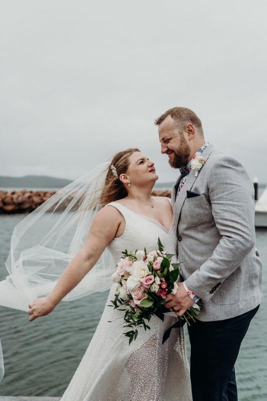 Real bride Annabel and her husband on the water, wearing the Lotus gown and Camila veil; a sequin a-line wedding dress by Karen Willis Holmes.
