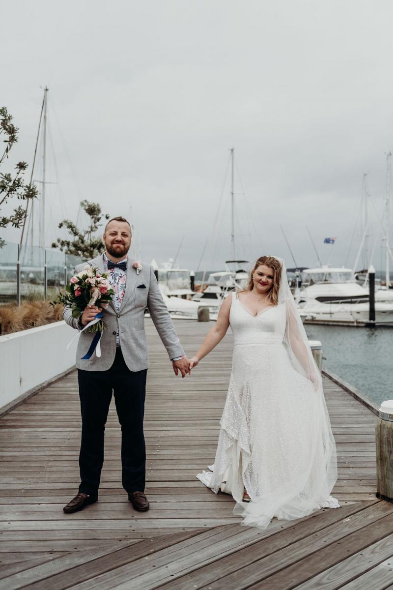 Real bride Annabel and her husband on the water, wearing the Lotus gown and Camila veil; a sequin a-line wedding dress by Karen Willis Holmes.