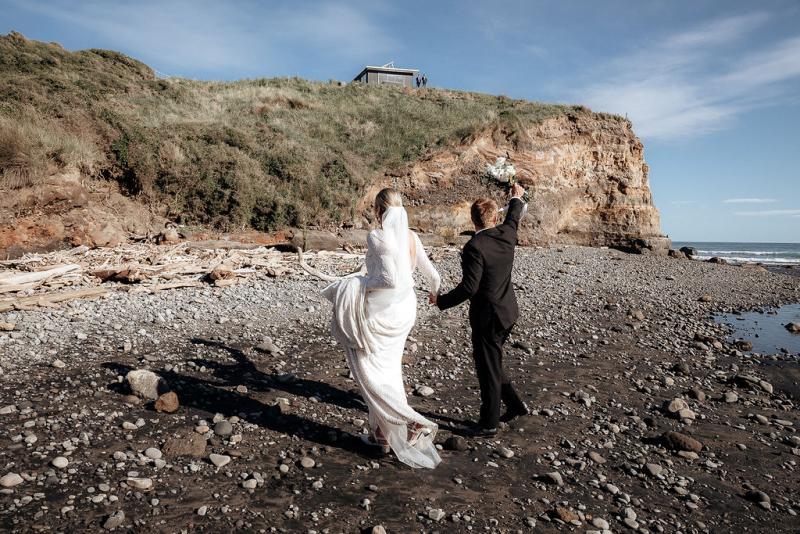 Black and white photo of KWH real bride Hannah and new husband Angus having a moment on the beach. She wears the high neckline Margaretta dress with long sleeves.