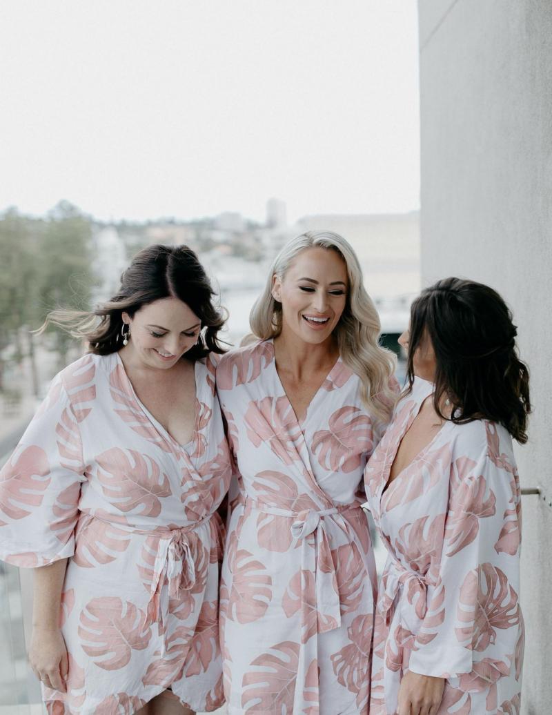KWH real bride Nicole with her bridesmaids wearing pink and white Monstera robes.
