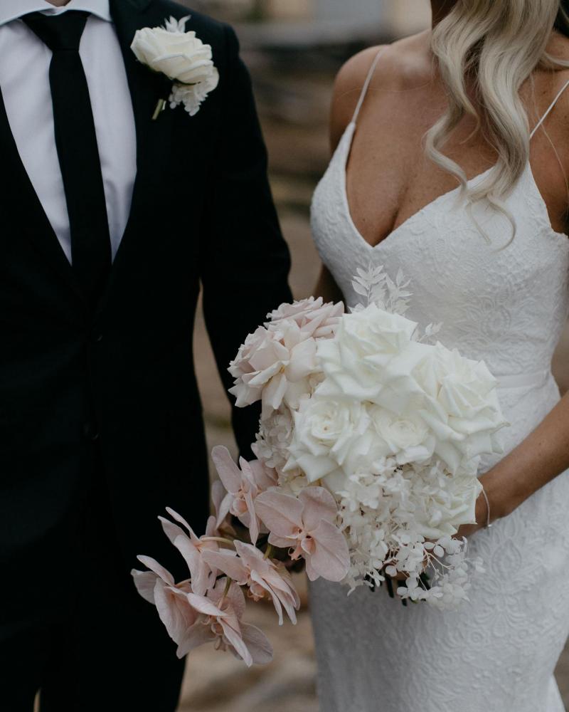 Upclose shot of KWH real bride Nicole and Chris. She holds her white and pink bridal bouquet by Ellebore while wearing her delicate lace Justine gown.